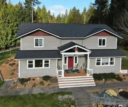 Aerial view of a homes new roof and siding surrounded by trees and landscaping.